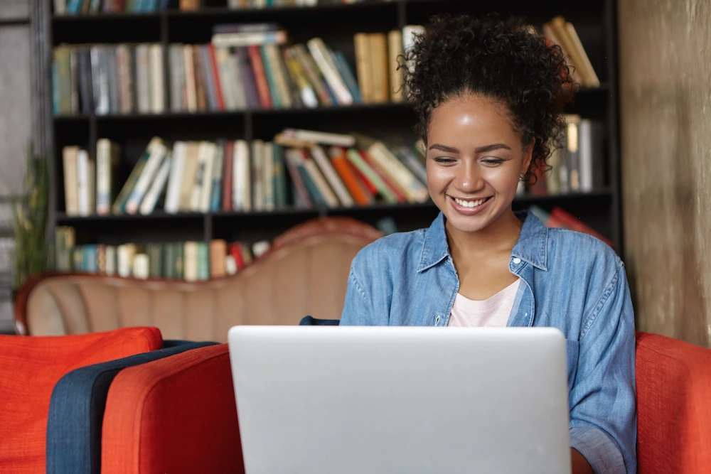 mulher sentada em uma biblioteca com seu laptop